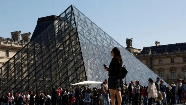 Visitors queue near the glass Pyramid to enter inside the Louvre Museum on a sunny spring day in Paris, France, April 18, 2025. REUTERS/Abdul Saboor