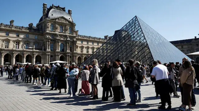 Visitors queue near the glass Pyramid to enter inside the Louvre Museum on a sunny spring day in Paris, France, April 18, 2025. REUTERS/Abdul Saboor