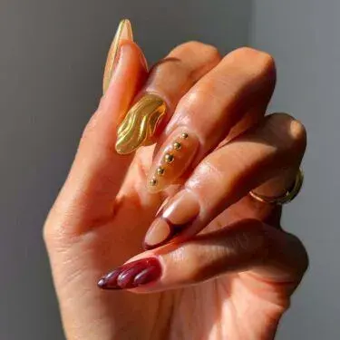 Long nails with structured gold and burgundy designs